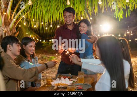 Das Paar nimmt mit einer Gruppe von Freunden an einer lustigen Party Teil. Stockfoto