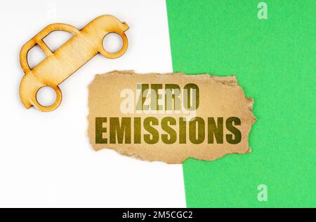 Ökologisches Konzept. Auf einer weiß-grünen Oberfläche ein Auto und ein Pappschild mit der Aufschrift - Zero Emissions Stockfoto