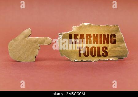 Geschäfts- und Bildungskonzept. Auf einer braunen Oberfläche zeigt eine Papphand auf ein Schild mit der Aufschrift „Lernwerkzeuge“ Stockfoto