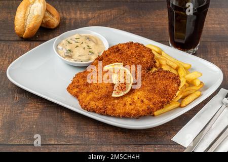 Hühnerschnitzel mit Butter und Kartoffelsalat auf weißem Porzellanteller Stockfoto