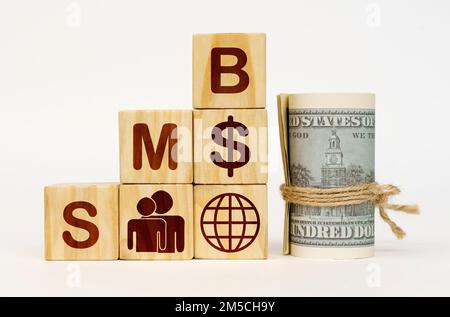 Geschäftskonzept. Auf einer weißen Oberfläche, Dollars und Würfel mit Bildern und der Inschrift - SMB Stockfoto