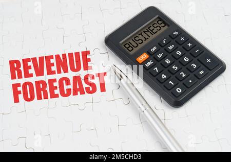 Geschäftskonzept. Auf den Rätseln befinden sich ein Taschenrechner und ein Stift neben der Aufschrift "Revenue Forecast" Stockfoto