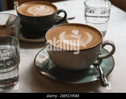 Zwei Tassen Cappuccino mit Latte Art auf einem Tisch in einem Café Stockfoto