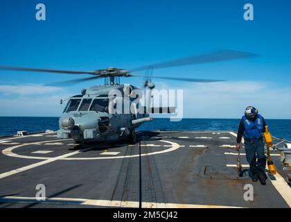 220301-N-EH998-1062 ATLANTISCHER OZEAN (März 1,2022) Boatswain’s Mate 3. Klasse David Wright holt Kreide und Ketten aus einem MH-60 Sea Hawk Helicopter, der dem Helicopter Maritime Strike Squadron (HSM) 26 zugewiesen ist, an Bord des geführten Raketenzerstörers USS Farragut (DDG 99), während er für das Surface Warfare Advanced Tactical Training (SWATT) unterwegs ist. Farragut ist Teil der Destroyer Squadron (DESRON) 26, die die Carrier Strike Group (CSG) 10 unterstützt. SWATT wird vom Naval Surface and Mine Warfighting Development Center (SMWDC) geleitet und soll die Kampffähigkeit, die Letalität und die Interoperabilität verbessern Stockfoto