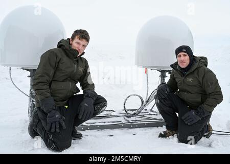 220302-N-JO245-1042 PRUDHOE BAY, Alaska (2. März 2022) – Bruce Billian (rechts), Chefwissenschaftler, und Tyler Brant, ein Ingenieur, dem Naval Information Warfare Center Atlantic zugeteilt, posieren für ein Foto vor kommerziellen Satellitenkommunikationsgeräten in Prudhoe Bay, Alaska. Billian und Brant testeten das Fanggerät, bei dem in der extremen Kälte im Norden Alaskas verbreitete Satellitenkonstellationen mit niedriger Erdumlaufbahn zum Einsatz kommen, bevor sie es in den USA nach Ice Camp Queenfish transportierten Eisübung der Marine (ICEX) 2022. Ice Camp Queenfish ist ein Lager, das auf einer Eisscholle 160 Seemeilen vom coa gebaut wurde Stockfoto