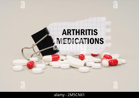 Medizinisches Konzept. Unter den Tabletten und Kapseln ist ein Clip mit Papier, auf dem steht - Arthritis Medikamente Stockfoto