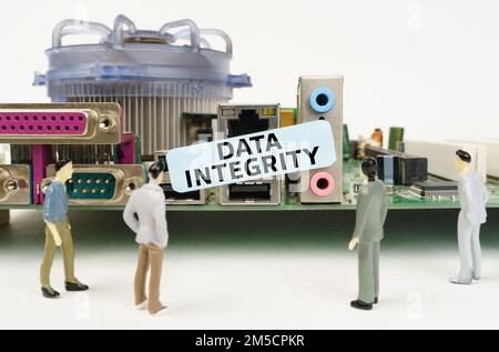 Technik und Computerkonzept. Figuren von Menschen stehen neben dem Motherboard und schauen auf den Aufkleber mit der Aufschrift „Data Integrity“ Stockfoto