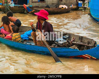 Siem Reap, Kambodscha - 12. August 2010: Kambodschaner leben auf Tonle SAP Lak, Frau, die Kinder auf dem Boot trägt. Stockfoto