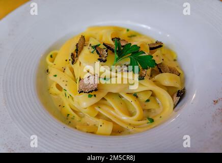 Frische Pasta mit Trüffelsauce, garniert mit rasierten schwarzen Trüffeln und rasiertem Parmesankäse in einem italienischen Restaurant, Centro Storico, Florenz, Italien Stockfoto