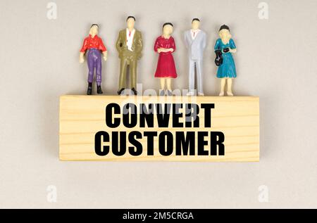 Geschäftskonzept. Auf dem Block mit der Aufschrift „Convert Customer“ befinden sich Miniaturfiguren von Menschen. Stockfoto