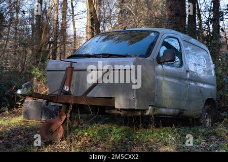 Verwitterter Peugeot Partner-Van, der in einen kleinen Wohnwagen mit rostigem Unterwagen, Gaskasten und Nasenrad im Wald umgewandelt wurde Stockfoto