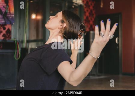 Seitliches Foto einer neuen Yoga-Lehrerin, die während ihres Vinyasa-Flow-Yoga-Trainings mit offenen Armen eine nach hinten gebogene Pose macht Stockfoto