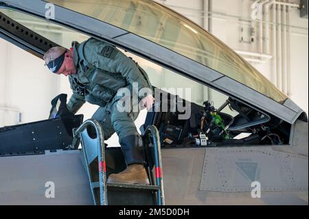 USA Air Force Captain Nathan Johnson, ein Kampfpilot der 90. Kampfgeschwader, verlässt das Cockpit eines F-22 Raptors auf der Joint Base Elmendorf-Richardson, Alaska, 2. März 2022. Die Eigenschaften des F-22 sorgen für einen Synergieeffekt, der die Letalität des F-22A gegen alle hoch entwickelten Bedrohungen in der Luft gewährleistet. Die Kombination aus Tarnkappen, integrierter Avionik und Supercruise verkleinert die Oberfläche-Luft-Raketenangriffsumfänge drastisch und minimiert die feindlichen Fähigkeiten, die F-22 zu verfolgen und anzugreifen. Stockfoto