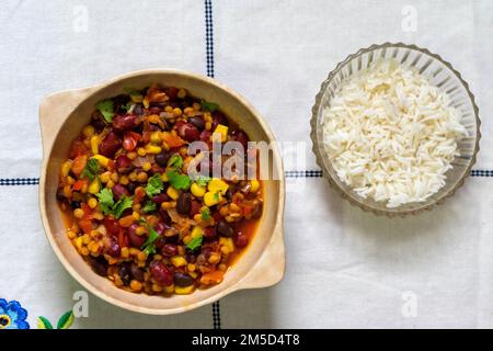 Drei Bohnen vegetarisches Chili. Aus schwarzen, weißen und roten Bohnen und Mais. Begleitet von weißem Reis.