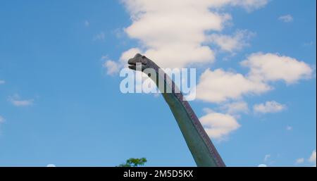 Park Attraction Place. Ein Dinosaurierkopf in Bewegung. Die Figur des steinzeitlichen Monsters in Nahaufnahme auf dem blauen Himmelshintergrund. Urlaub, Urlaub, Urlaub. Stockfoto