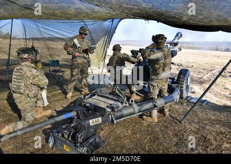 USA Fallschirmjäger mit Alpha Battery, 4. Bataillon, 319. Artillerie-Regiment, 173. Brigade führen eine Feuermission mit einem M119 m starken Howitzer auf dem Grafenwoehr-Trainingsgelände des 7. Armeeübungskommandos, Deutschland, am 3. März 2022 durch. Die 173. Brigade ist die USA Armee-Notfalleinsatztruppe in Europa, fähig, Einsatzkräfte überall in den USA zu projizieren Zuständigkeitsbereiche der Kommandos Europa, Afrika oder Zentralafrika. Stockfoto