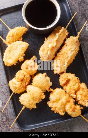 Kushikatsu ist eine Spezialität in Osaka, die aus paniertem und dann frittiertem Gemüse, Fleisch und Eiern besteht, die auf dem Teller auf dem Tisch verstaut sind. Vertikal Stockfoto