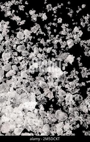 Meersalz, Flour de sel, Nahaufnahme von Kristallen auf einer schwarzen Oberfläche. Außerdem flor de Sal, ein Salz, das eine dünne empfindliche Kruste auf verdampfendem Meerwasser bildet. Stockfoto