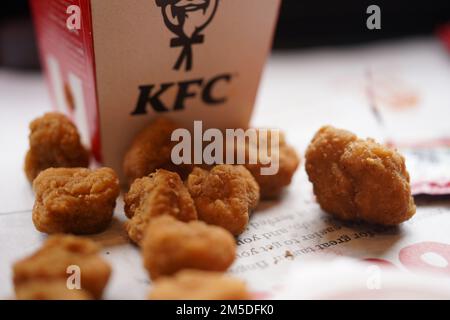 Gebratenes Popcorn-Hähnchen auf dem Restaurantteller mit natürlichem Sonnenlicht. KFC Restaurant. KFC ist eine beliebte Fast-Food-Kette, bekannt als Kentucky Fried Chicken. Stockfoto