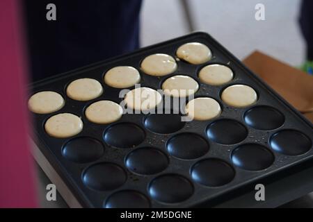 Ich mache morgens Mini-Pfannkuchen auf der Pfannkuchenmaschine. Stockfoto
