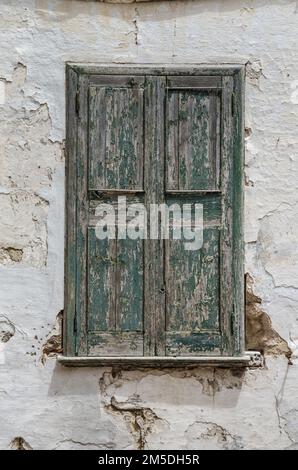 Ein Fenster mit wetterabgenutzten grünen Holzläden in einem alten Gebäude auf der spanischen Insel Menorca Stockfoto