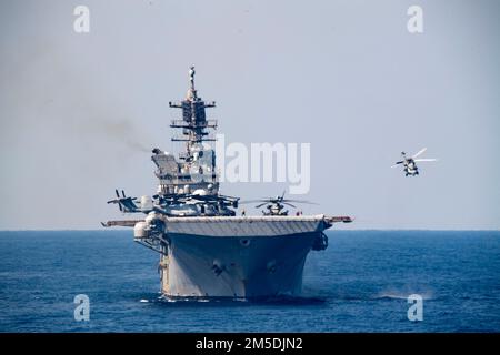 PHILIPPINE SEA (4. März 2022) Ein MH-60s Sea Hawk Hubschrauber, der der Helicopter Sea Combat Squadron (HSC) 25 zugeteilt ist, verlässt das nach vorn ausgesetzte Amphibienschiff USS America (LHA 6) während des Flugbetriebs. America , das führende Schiff der America Amphibious Ready Group, ist zusammen mit der 31. Marine Expeditionary Unit im Zuständigkeitsbereich der US-amerikanischen 7.-Flotte tätig, um die Interoperabilität mit Verbündeten und Partnern zu verbessern, und dient als einsatzbereite Eingreiftruppe zur Verteidigung von Frieden und Stabilität in der Region Indo-Pazifik. Stockfoto