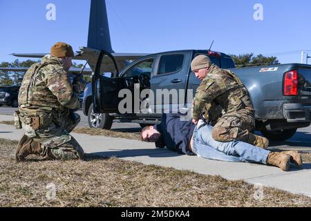 Master Sgt. Nicholas Myers, ein Mitglied der Sicherheitskräfte aus dem Jahr 106., funkt zum Verteidigungszentrum der Basis, während Staff Sgt. Noel Ruiz, ein Mitglied der Sicherheitskräfte aus dem Jahr 106., eine Person während einer Übung zum Einrichtungsbruch im 106. Rettungsflügel der NY Air National Guard, Francis S. Gabreski Air National Guard Base, durchsucht. Westhampton Beach, New York, 4. März 2022. Während der Ausbildung hielt der inhaftierte Verdächtige nicht am Basiseingang an und wurde anschließend von 106. Sicherheitskräften festgenommen. Stockfoto