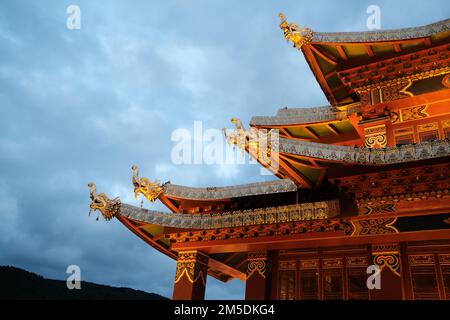 Chinesisches Tempeldach im Himmelshintergrund. Traditionelles chinesisches Dach mit orangefarbenen Details und goldenen Ornamenten. Orangefarbenes Dach auf dem Tempel in Shangri-l Stockfoto