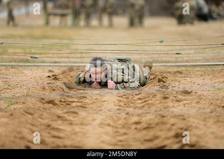 Sgt. Joy Quary, Mitglied der Alpha Company, 1. Bataillon, 158. Artilleriegesiment, 45. Artilleriebrigade, Oklahoma Army National Guard, kriecht unter Stacheldraht, während sie versucht, einen Hinderniskurs zu absolvieren. Der Hinderniskurs war Teil des Wettbewerbs „Best Warrior“ im Camp Gruber Training Center, Oklahoma, 3. März 2022. Der Wettbewerb „Bester Krieger“ ist ein dreitägiges jährliches Event, bei dem hochrangige Soldaten ihre Fähigkeiten in einer Vielzahl von Aufgaben und Übungen unter Beweis stellen. Die Wettbewerber werden Tests in der Landnavigation, Schießkunst und Waffenkompetenz, einem Asau, bestehen Stockfoto