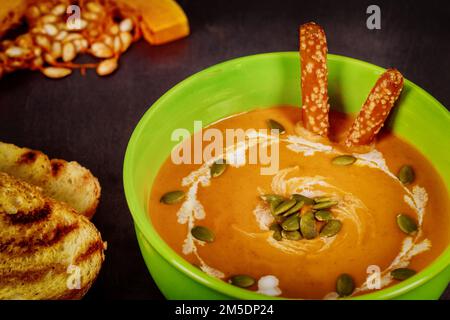 Köstliche Schüssel mit Gemüse-Kürbissuppe, garniert mit organischen Kürbiskernen Stockfoto