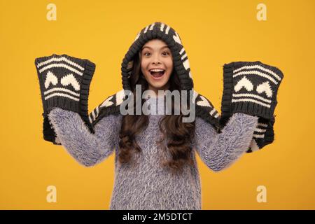 Ein erstaunlicher Teenager. Warmer Hut mit Kapuze und Schal. Mode glücklich junge Frau in gestrickten Hut und Pullover mit Spaß über bunten blauen Hintergrund begeistert Stockfoto