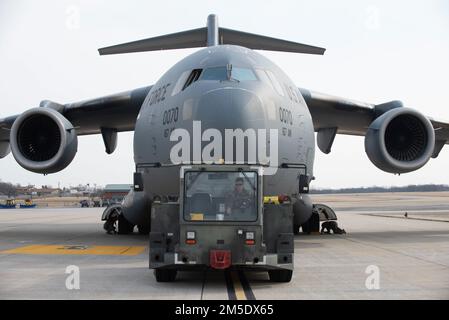 USA Air Force Master Sgt. Travis Hall, ein Betreuer der 167. Maintenance Group, betreibt einen Schlepper, um ein C-17 Globemaster III Flugzeug auf der Fluglinie am 167. Airlift Wing, Martinsburg, West Virginia, am 5. März 2022 zu transportieren. Das Abschleppen von Flugzeugen spart Treibstoffkosten und ermöglicht präziseres Parken. Stockfoto