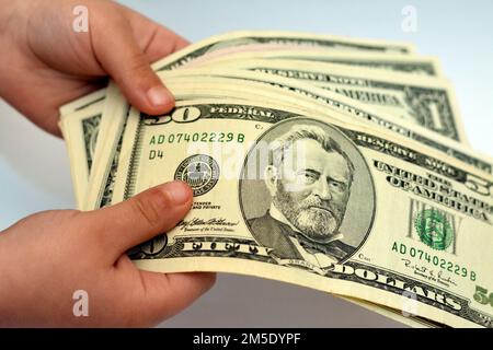 50 50-Dollar-Banknotengeld-Schein in der Hand eines kleinen Kindes zeigt das Profil des US-Präsidenten Ulysses S. Grant, Economic and Fi aus dem Jahr 18. Stockfoto