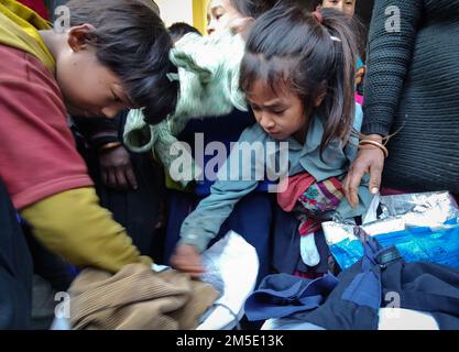 Dhading, Bagmati, Nepal. 27. Dezember 2022. Kinder aus der Chepang Gemeinde versuchen, die gewünschte warme Kleidung für ihre Familie im Dorf Hekrang Benighat Rorang im Dhading-Viertel auszuwählen, das am 27. Dezember 2022 etwa 55 km von der Hauptstadt Kathmandu, Nepal, entfernt ist. Heartbeat, eine soziale Organisation zusammen mit einzelnen Spendern, verteilte warme Kleidung und Schreibwaren, Kunstmaterialien, Essen an Kinder der Chepang Gemeinde, warme Kleidung an Familienmitglieder. (Kreditbild: © Sunil Sharma/ZUMA Press Wire) Stockfoto