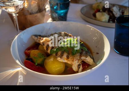 Provenzalische Küche, gegrilltes Weißfischfilet vom Seabarsch, serviert mit Kartoffeln, Tomaten und Bouillabaisse-Fischjus im französischen Restaurant Stockfoto
