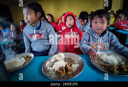 Dhading, Bagmati, Nepal. 27. Dezember 2022. Kinder aus der Chepang-Gemeinde sind bereit, nach dem Tragen warme Kleidung zu essen im Hekrang Dorf Benighat Rorang im Dhading-Viertel, rund 55 km von der Hauptstadt Kathmandu, Nepal am 27. Dezember 2022. Heartbeat, eine soziale Organisation zusammen mit einzelnen Spendern, verteilte warme Kleidung und Schreibwaren, Kunstmaterialien an Kinder der Chepang Gemeinde, warme Kleidung an Familienmitglieder. (Kreditbild: © Sunil Sharma/ZUMA Press Wire) Stockfoto