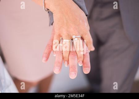 Nahaufnahme der Hände eines frisch verheirateten Paares mit Eheringen. Stockfoto