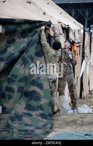 USA Armeespezialisten, die dem 2. Bataillon, dem 34. Panzerregiment, dem 1. Panzerbrigade-Kampfteam, der 1. Infanteriedivision zugeteilt sind, decken ihr Zelt mit Tarnnnetzen ab, 6. März 2022, im Militärgebiet Hradiště im Nordwesten der Tschechischen Republik. Saber Strike 2022 ist eine multinationale Übung, die eine realistische Kampfausbildung für Mitglieder des NATO-Dienstes in der europäischen Region bietet. Stockfoto