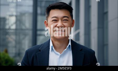 Portrait pensive träumen Denken Regisseur Architekt männlich in der Stadt draußen blickt weg vom Bürogebäude Kopf drehen Blick auf Kamera Asiatisch 40s Stockfoto