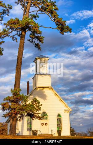 Newport, Tennessee, USA - 6. November 2022: Eine kleine alte Kirche befindet sich auf einem Hügel mit Blick auf den Westen, während die Sonne untergeht, und wirft ein goldenes Licht auf die Kleinen Stockfoto