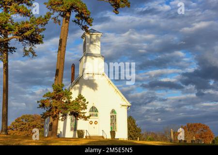 Newport, Tennessee, USA - 6. November 2022: Eine kleine alte Kirche befindet sich auf einem Hügel mit Blick auf den Westen, während die Sonne untergeht, und wirft ein goldenes Licht auf die Kleinen Stockfoto