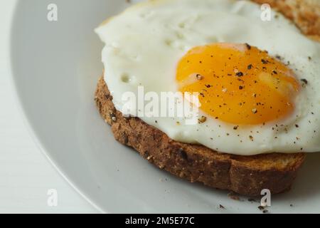 Gebratenes Ei auf einer Scheibe getoastetes Brot mit schwarzem Pfeffer auf der Oberseite Stockfoto