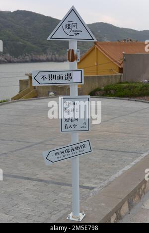 Eine vertikale Aufnahme eines Straßenschilds mit mehreren Texten auf Chinesisch, die Ziele zeigen Stockfoto