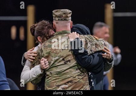 FORT Knox, Ky. - LT. Oberstleutnant Sean McNichol umarmt seine Familie Auf Wiedersehen vor dem Einsatz nach Deutschland am 7. März. Das Hauptquartier des V-Corps wird zusätzliche Kommando- und Kontrollbefugnisse über die USA übernehmen Armee in Europa. Stockfoto