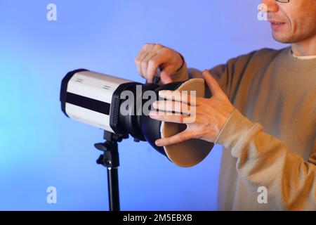 Einen Blitz im Studio von einer Person auf blauem Hintergrund in den Schatten stellen Stockfoto