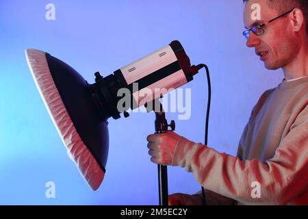 Kosmetikschale mit Diffusor auf Blitz und Person auf blauem Hintergrund Stockfoto