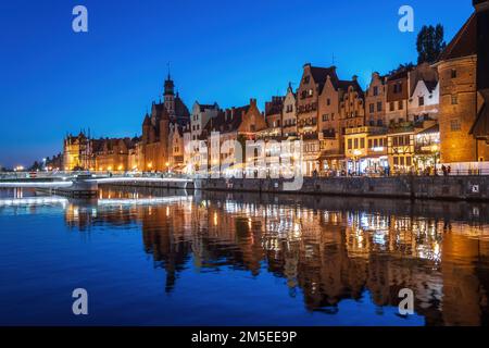Nachteinbruch in Danzig in Polen. Skyline der Altstadt mit Reflexionen am Motlawa River, historischen Giebelhäusern und Toren entlang Long E Stockfoto