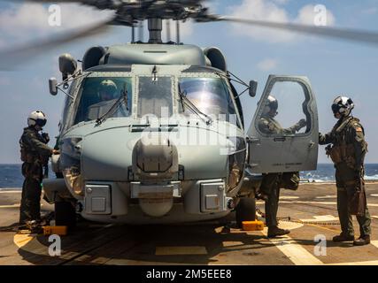 PHILIPPINE SEA (7. März 2022) Mitglieder der Hubschrauber-Staffel HMS (Helicopter Maritime Strike Squadron) -51 führen während des Flugbetriebs an Bord des Arleigh-Burke-Class Guided-Missile Destroyer USS Ralph Johnson (DDG 114) einen Besatzungswechsel durch. Ralph Johnson ist der Task Force 71/Destroyer Squadron (DESRON) 15, dem größten nach vorn verlegten DESRON der Marine, und der Hauptstreitkraft der US-7.-Flotte zugewiesen. Stockfoto