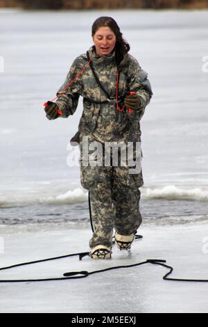 Airman 1. Class Julia Childers, ein Sicherheitsdienst Airman mit dem 128. Air Tanken Flügel der Wisconsin National Guard in Milwaukee, nimmt am 7. März 2022 am Big Sandy Lake an der South Post in Fort McCoy, Wisconsin, Teil. Childers war Student im Cold-Weather Operations Course (CWOC), Klasse 22-05 in Fort McCoy. Die Schulung ist Teil des Lehrplans für CWOC. Ein großes Loch im Eis am See wird von CWOC-Mitarbeitern geschnitten, dann folgt ein sicheres und geplantes Regime, damit jeder Teilnehmer in das eisige Wasser springen kann. Notfallpersonal ist ebenfalls in der Nähe Stockfoto