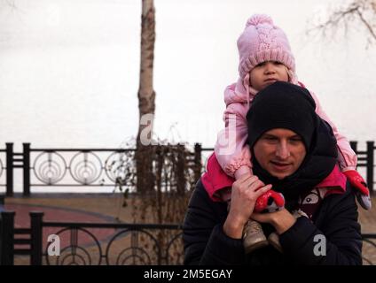 Kiew, Ukraine 15. Dezember 2019: Vater trägt ein Kind auf seinen Schultern. Stockfoto